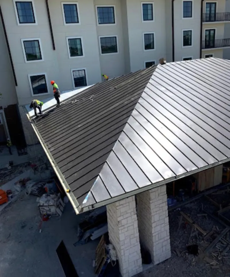 Crew installing standing seam metal roof panels on a commercial project in Waynesville